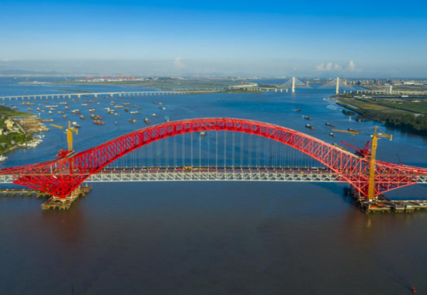 明珠湾大桥位于广州市南沙区龙穴南水道之上，是粤港澳大湾区的重要连接通道。大桥工程全长约10.42公里，主线全长约9.1公里，主桥采用中承式六跨连续钢桁拱桥，全长1016米，为同类型桥梁最大跨度。气势恢宏的明珠湾大桥绵延伸向远方，将南沙多条核心主干道紧紧连在一起，构筑了明珠湾区内部核心交通环，是广州面向粤港澳大湾区建设的交通枢纽工程和地标性建筑。图为南沙明珠湾大桥。