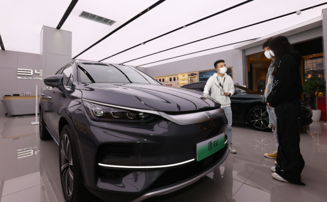 比亚迪店内，一名销售人员（左）正在向两位顾客介绍车辆信息。深圳特区报记者 杨浩翰 摄