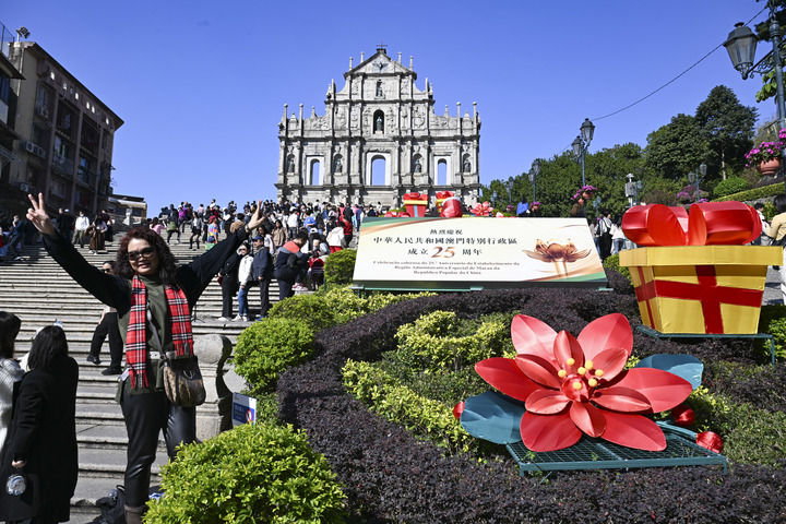 游客在澳门大三巴牌坊庆祝布景旁留影（2024年12月18日摄）。新华社记者 程一恒 摄