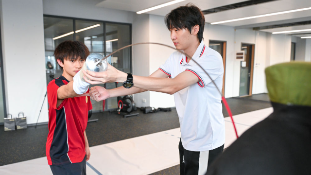 ↑图为广东现代五项运动协会教练员肖勇炫（右）纠正广州市中黄港澳子弟学校港籍生张嗣涛击剑技术细节（6月19日摄）。新华社记者肖恩楠摄
