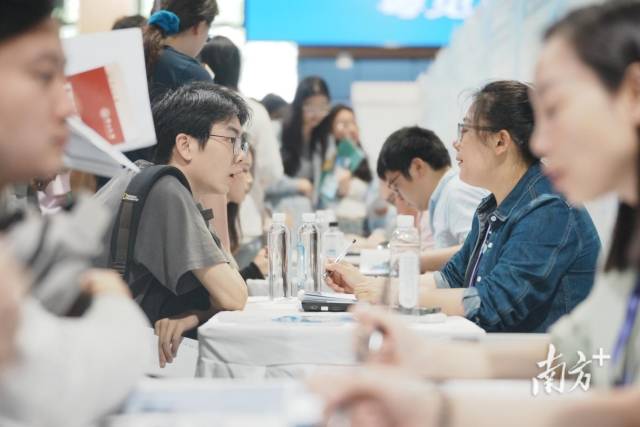 “百万英才汇南粤”武汉招聘会现场火爆，企业招聘展位座无虚席，面试洽谈对接需求。