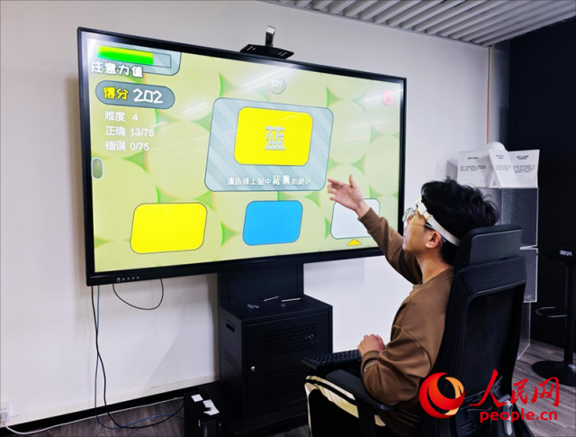 广州琶洲实验室工作人员演示脑机接口设备如何操作专注力训练游戏。人民网 朴馨语摄